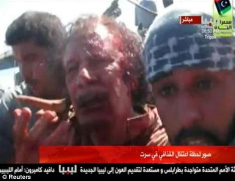 Former Libyan leader Muammar Gaddafi, covered in blood, is pulled from a truck by NTC fighters in Sirte before he was killed